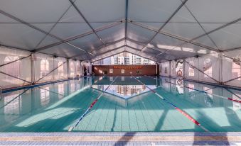 There is an indoor swimming pool with a large roof covered in white and blue tiles at Nuomo Hotel