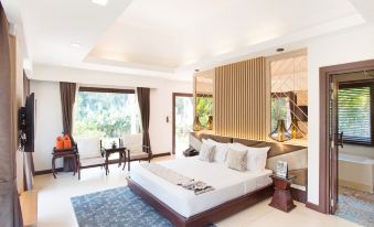 a large bed with a wooden headboard is in the middle of a room with white walls and a blue rug at Mida Resort Kanchanaburi
