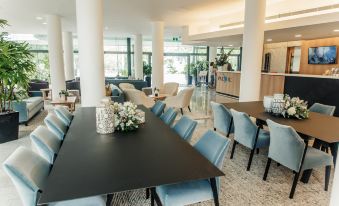 a large , well - lit dining room with a black dining table surrounded by blue chairs and couches at Mercure Brisbane Spring Hill