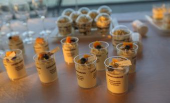 a table is set with several small cups filled with desserts , including ice cream and cupcakes , and a tray of cookies at Lucen