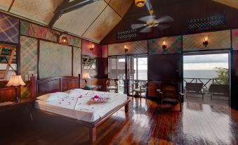 The bedroom features large windows and wooden floors, offering an ocean view beside the bed at Sipadan Kapalai Dive Resort