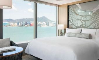 A bedroom with large windows offers a view of the water and city from an elevated bed at Hyatt Centric Victoria Harbour Hong Kong