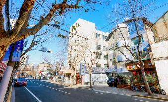 On both sides of the street, there are trees and buildings, and the sidewalk is empty at Zhotels (Shanghai West Nanjing Road Westgate Mall)