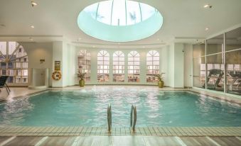 a large indoor swimming pool with a glass ceiling and white walls , surrounded by windows that allow natural light to fill the space at Cititel Penang