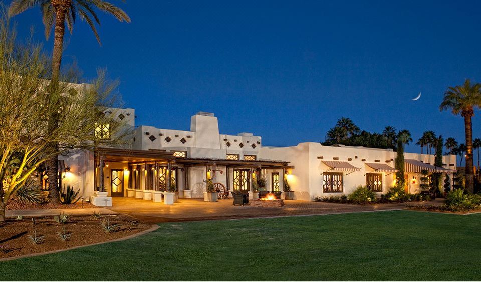 a large white building with a thatched roof , surrounded by grass and trees , at night at The Wigwam