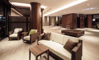 a modern , well - lit living room with various pieces of furniture and couches arranged around a coffee table at HOTEL MYSTAYS Fuji Onsen Resort