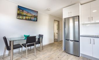 a small , well - equipped kitchen with a dining table and chairs , as well as a refrigerator and a microwave at Hamilton on Beaumont