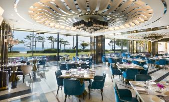 a large , modern restaurant with multiple dining tables and chairs , surrounded by a view of the ocean at Paradise Hotel Busan