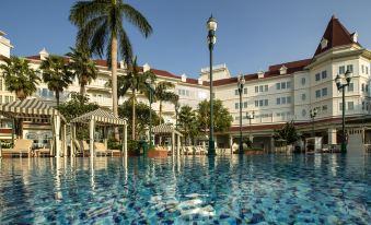 A large swimming pool is located in front of an upscale resort or hotel at Hong Kong Disneyland Hotel