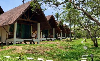 a row of wooden cottages surrounded by green grass and trees , with a pathway leading to them at Phayamas Private Beach Resort and Island Brew - Adults Only