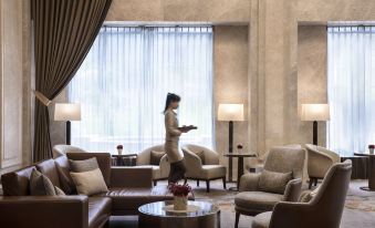 a woman in a room with chairs and a couch , while she is standing in the center of the room at Hotel Valletta