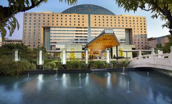 A large building with a view of the outdoors and water in front, featuring the main entrance at Kempinski Hotel Beijing Yansha Center