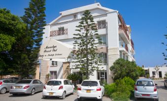 a white building with multiple cars parked in front of it , under a clear blue sky at Manolya Hotel