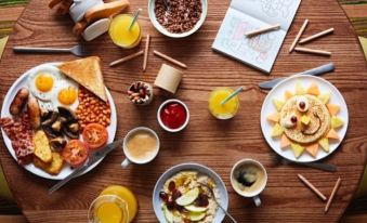 a dining table with a variety of food and drinks , including a bowl of cereal , cups of coffee , and plates of food at Premier Inn Dover East