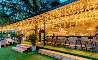 At night, a photo captures a restaurant with illuminated lights on the side and tables in front at Nostalgia Hotel (Beijing Lama Temple, Nanluogu Lane,)