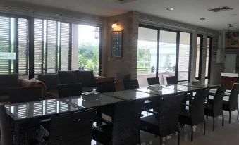 a modern , well - lit conference room with large windows and black furniture , surrounded by white walls and a green tree in the background at The Sept Korat