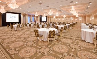 a large banquet hall filled with round tables and chairs , ready for a formal event at Clayton Plaza Hotel & Extended Stay