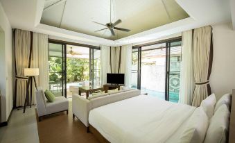 a spacious bedroom with a large bed , a tv , and a view of a swimming pool at Robinson Khao Lak