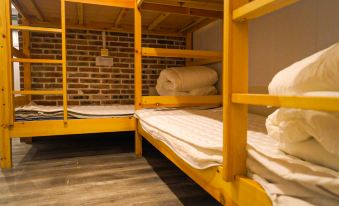The bedroom contains bunk beds and two metal bedspreads, along with other furniture at Paoju Factory Youth Hostel (Beijing Summer Palace Subway Station Branch)