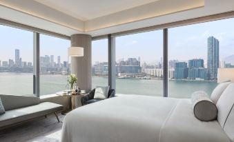 The bedroom has large windows that provide views of the city and water, but the bed is unmade at Hyatt Centric Victoria Harbour Hong Kong