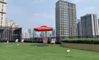 In front of the park, there is a lawn with green grass and chairs, providing a view of the buildings behind it at CitiGO Hotel, West Nanjing Road, Jing'an Temple, Shanghai