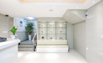 There is a white room with numerous plants in the center, accompanied by an adjacent office at Zhotels (Shanghai West Nanjing Road Westgate Mall)