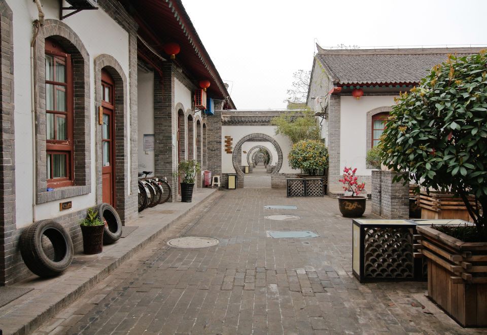 On the other side of the courtyard, there is another building with an archway and small shops at 7 Sages International Youth Hostel