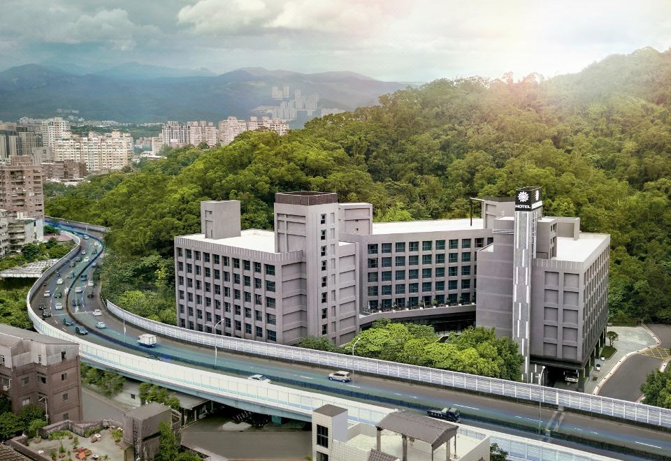 a modern city with a highway running through it , surrounded by buildings and trees , including a large building on the side of a hill at Platinum Hotel