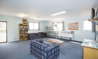 a room with a blue couch , bookshelf , and various items such as books , toys , and a fire extinguisher at Big4 Townsville Gateway Holiday Park