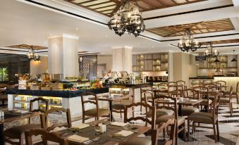 a large , well - lit dining room with wooden tables and chairs arranged for a group of people at Melia Purosani Yogyakarta