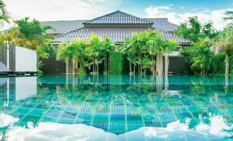 a large house surrounded by a swimming pool , with several people enjoying their time in the pool at Palm Sweet Resort