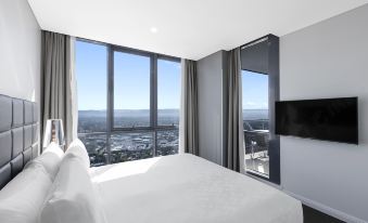 a modern bedroom with a large window overlooking the city , providing a view of the surrounding cityscape at Meriton Suites Southport