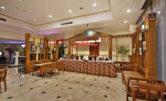 a large dining room with a long wooden table and chairs , surrounded by benches for guests at Jayakarta Hotel Jakarta