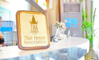 a hotel lobby with a reception desk , where a man is standing behind the counter at Bay Hotel Srinakarin