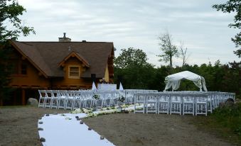 a large outdoor wedding ceremony taking place in front of a house , with rows of chairs set up for guests at Fiddler Lake Resort