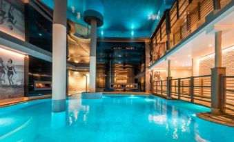 an indoor swimming pool with a blue light , surrounded by wooden pillars and a ceiling with lights at Preidlhof Luxury Dolce Vita Resort
