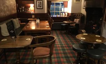 a cozy restaurant with wooden tables and chairs , green checkered carpet , and a bar area at The Engine Inn