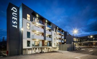 a modern apartment building with multiple balconies and lights , under a blue sky at night at Quest Wodonga