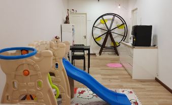 a playroom with a blue slide , wooden floors , and various toys such as an igloo and a ferris wheel at G Residence