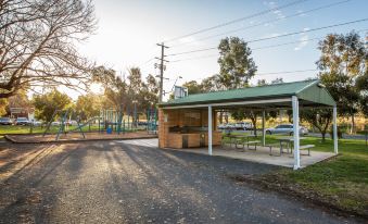 a large , green roofed shelter with a carport in front of it and trees surrounding the area at Borderland Wodonga Holiday Park