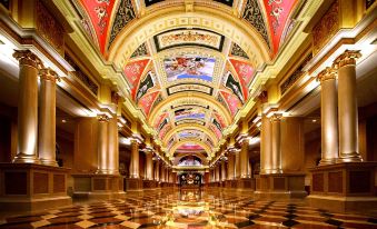The lobby and hallway of a grand building feature an ornate ceiling and paintings on the walls at The Venetian Macao
