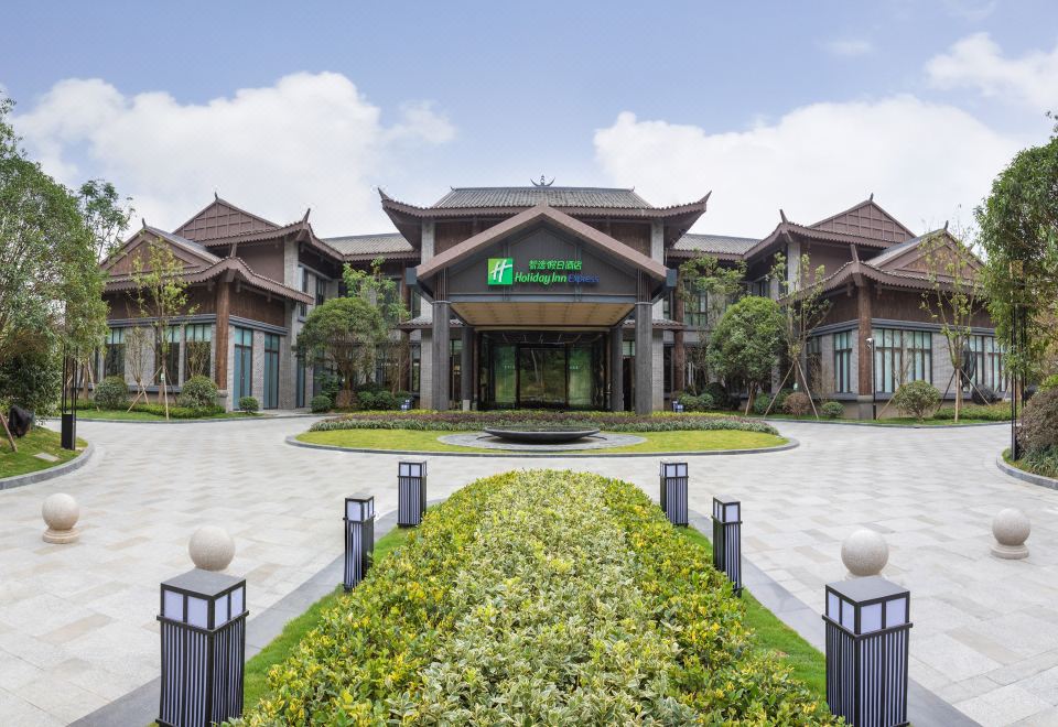 a large building with a green sign on the front , surrounded by trees and grass at Holiday Inn Express