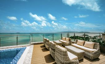 a wooden deck overlooking the ocean , with several chairs and couches placed around it for relaxation at Navada Beach Hotel