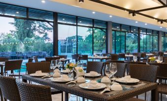 a dining room with a table set for a meal , surrounded by chairs and large windows at KS Hotel