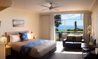 a well - lit hotel room with a bed , couch , and balcony , offering a stunning view of the ocean at Kangaroo Island Seafront