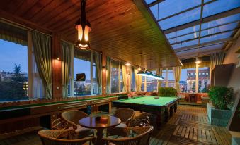 a pool table is set up in a room with wooden floors and large windows at Paradise Hotel