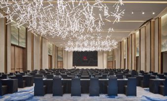 A large, well-lit room with rows of chairs in the front at Hangzhou Marriott Hotel Qianjiang
