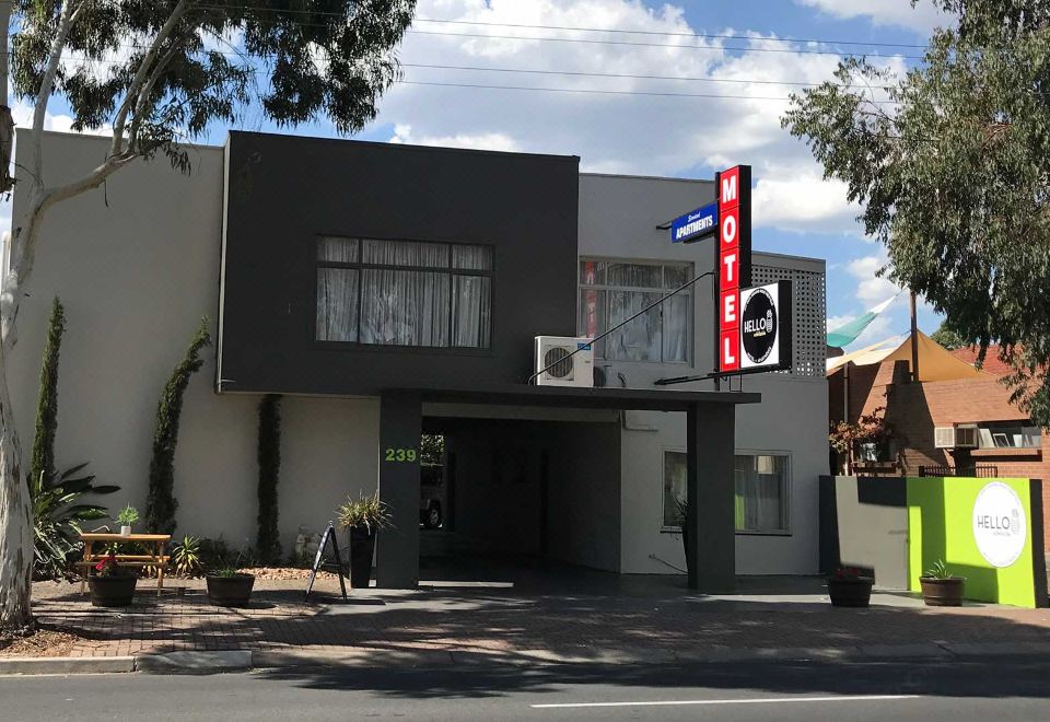 "a modern building with a black and white color scheme , a red sign that reads "" motel ,"" and a street view of the" at Hello Adelaide Motel and Apartments