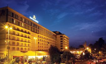 "a large hotel building with a sign that says "" hotel hi "". several cars parked in front of it" at Pearl Continental Hotel, Lahore