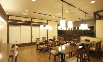 a large dining room with wooden tables and chairs , pendant lights hanging from the ceiling at Sun Palace Hotel